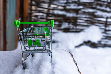 Empty shopping cart green in winter on the street.