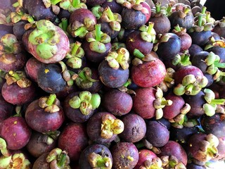 Mangosteen queen of fruit. Healthy fruits mangosteen background, dark mangosteen in a traditional local market, bunch of mangosteen ready to eat, summer tropical Asia fruit
