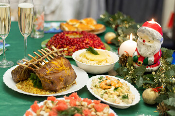 Fototapeta na wymiar A festive table with many delicious dishes. Lamb rack, two glasses of champagne, salads and snacks on the festive table.