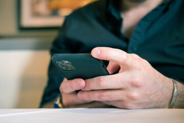 Cropped image of a mans hands holding a black smart phone, mobile phone in the palms of a person. Perfect for composite and mock ups.