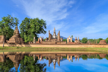 Obraz premium Buddha statue and Pagoda in ruined monastery complex at Wat Mahathat temple with reflection, Sukhothai Historical Park, Thailand