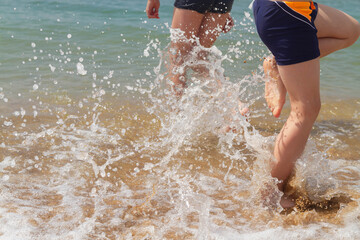 Children run on the waves of the sea and play in the spray of the waves.