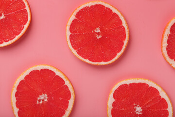Patterns of slices of juicy grapefruit on a pink background, a beautiful pattern.