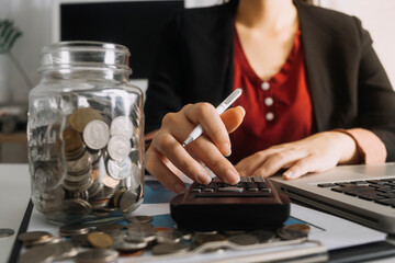 Businesswomen hands working with finances about cost and calculator and laptop with tablet, smartphone at office in morning light