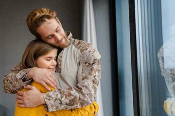 Happy military man smiling while hugging her daughter in his hands