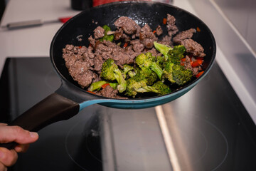 Skillet of ground beef stir fry with vegetables broccoli pepper and onion on an electric stove on high speed Cordoba Argentina