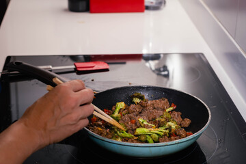 Skillet of ground beef stir fry with vegetables broccoli pepper and onion on an electric stove on high speed Cordoba Argentina