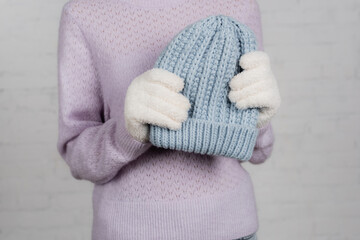 Fototapeta na wymiar Cropped view of woman in warm sweater and gloves holding knitted hat on white background