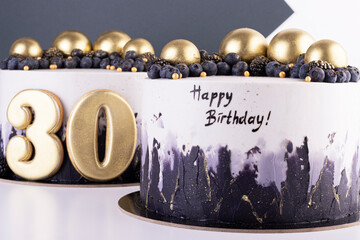 Festive black and white cakes 30 years old with golden balls and dark berries
