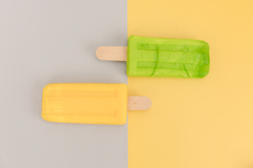 Ice cream stick on gray and yellow background.