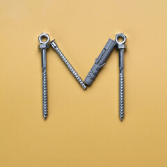 Alphabet letter M made of bolts, screws, typeset