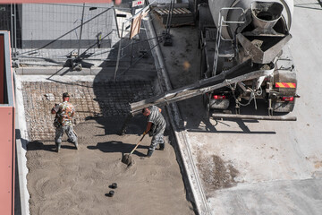 Group of builders working together on pouring cement during an upgrade of public projects to fix...