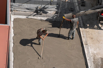Group of builders working together on pouring cement during an upgrade of public projects to fix...