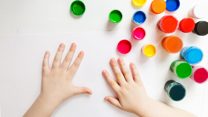 baby hands and gouache paint cans on a white background.