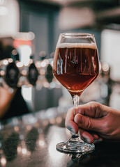 man holds a glass of beer in his hand at the bar or pub