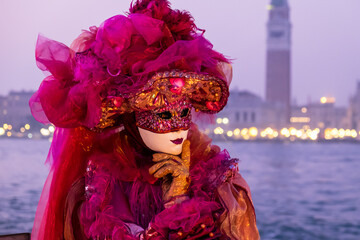 Fototapeta na wymiar Venice, Italy - February 18, 2020: An unidentified woman in a carnival costume in front of Piazza San Marco, attends at the Carnival of Venice.
