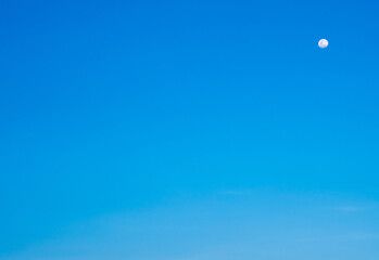 See the moon in the clear blue sky during the day