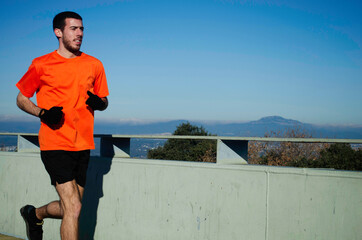 runner in orange t-shirt running with blue sky day. sport concept. image with copy space