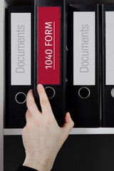 1040 Form. Folder with label on the shelf of a lawyer. Red label with text in focus.