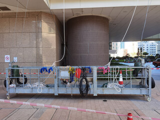 suspended cradle or steeplejack used by workers to access and clean windows of typical high rise building or skyscraper in Hong Kong before Christmas or New Year