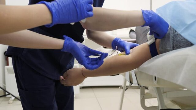 Professional doctors in medical gloves take blood from women in a test tube for analysis of coronavirus research in a modern clinic.