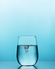 Fresh water with bubbles in a glass on the blue background