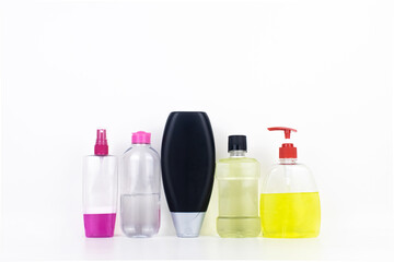 Isolated bottles of detergents on a white background. The hand takes the jars of detergents. In the photo, shampoo, micellar water, liquid soap and mouthwash. Household chemicals in colored containers