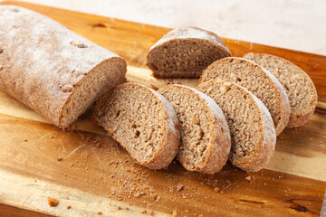 Close-up fresh chopped brown rye bread, slices on wooden cutting board