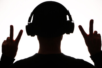 Wireless technology - Dark silhouette in headphones listens to music on a white background.