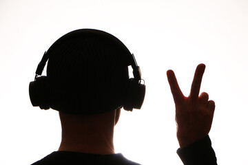 Wireless technology - Dark silhouette in headphones listens to music on a white background.