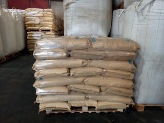 Chemical fertilizers Packed in stacked sacks with clear plastic wrapped around stacked on wooden pallets orderly. In the warehouse waiting for delivery