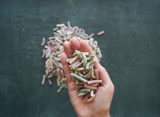 Handful of dried tricolor pasta in palm on a one hand