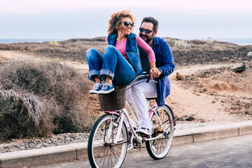 Joyful love friendship concept - happy adult caucasian, couple having fun with bicycle in outdoor leisure activity. concept of active playful people with bike during vacation - everyday joy lifestyle