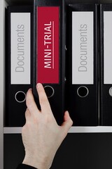 Mini-Trial. Folder with label on the shelf of a lawyer. Red label with text in focus.