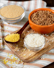 Rice, buckwheat, amaranth and millet in bowls on a brown wooden table. Gluten-free cereals	