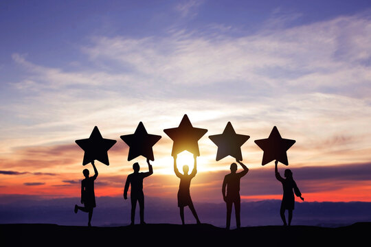 Silhouette peoples holding star with colorful dramatic sky at sunset. Service rating, satisfaction concept