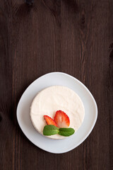 Top view on cake decorated with fresh strawberries on white plate. Wooden background. Vertical frame