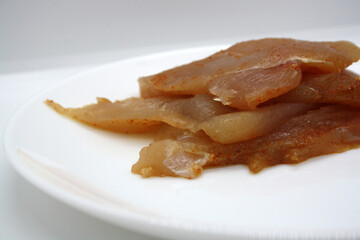 Chicken fillet pieces on a white plate.