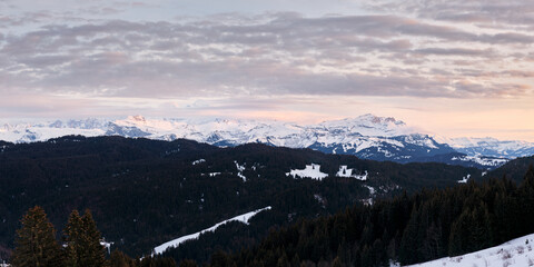 panorama sur la chaine du Mont Blanc enneigée dans les Alpes françaises au coucher du soleil depuis la station des Gets en France.