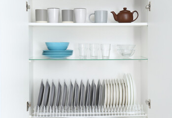 Open kitchen cabinet with different clean dishware