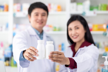 White plastic bottle medicine on holding hand man and woman pharmacist asian in drugstore Thailand close up and selective focus