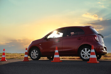 Fototapeta na wymiar Traffic cones near red car outdoors. Driving school exam