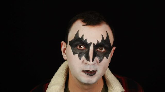 Man in demon makeup making funny faces on black background