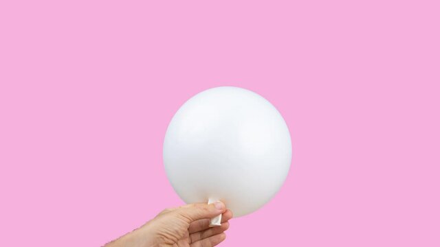 White balloon being blown up against pink background