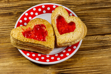 Heart shaped puff cookies with jam on a wooden table. Dessert on Valentine`s Day
