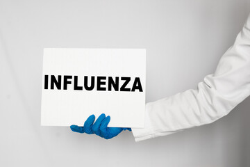 The doctor's blue - gloved hands show the word INFLUENZA - . a gloved hand on a white background. Medical concept. the medicine