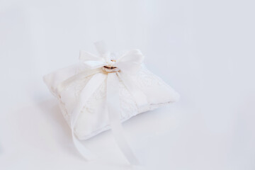 Fototapeta na wymiar Two golden engagement wedding rings at white small decor pillow cushion with ribbon 