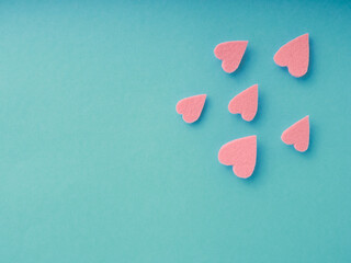 Isolated felt hearts soar over a blue background with copy space