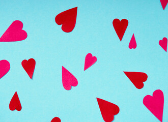 Top view on red and pink paper hearts on blue background