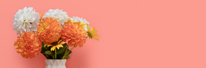 Banner wtih bouquet of dahlia flowers in vase in front of coral background. Springtime composition with copyspace.